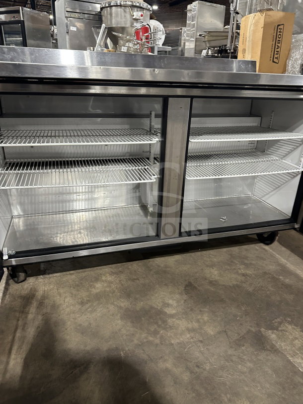 True TWT-60 stainless steel refrigerated worktop table with two doors, up-turned backsplash, poly-coated racks, on casters.