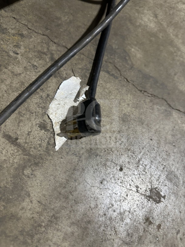 Electrical plug of True Commercial Refrigerated Worktop Table, 115V, for model TWT-60, seen resting on a concrete floor.