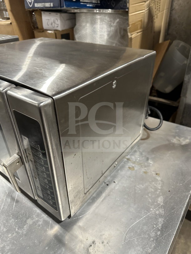 Menumaster RFS12TSW commercial stainless steel microwave oven on countertop, digital push button control, 120V, visible wear.