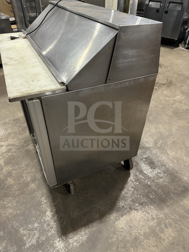 Commercial stainless steel 2-door refrigerated prep table with cutting board on casters; electric powered; visible wear.