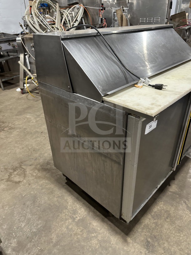 Commercial stainless steel 2-door refrigerated prep table with cutting board and casters, showing power cord and sturdy build.