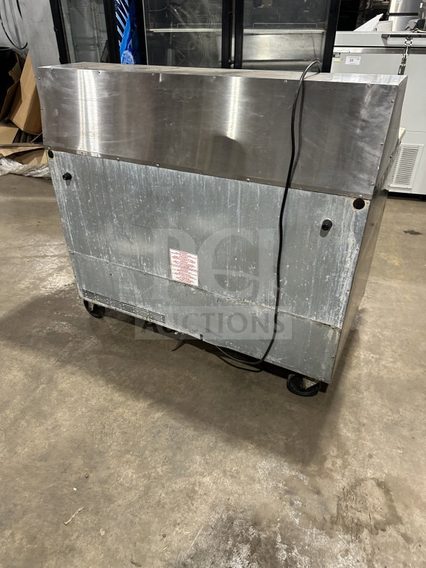 Commercial stainless steel 2-door refrigerated prep table with cutting board, electric powered, on casters. Moderate wear.