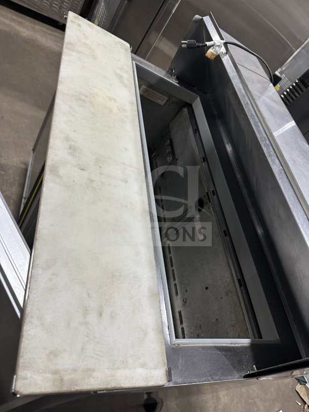 Commercial stainless steel 2-door electric refrigerated prep table with cutting board, on casters, minor wear.