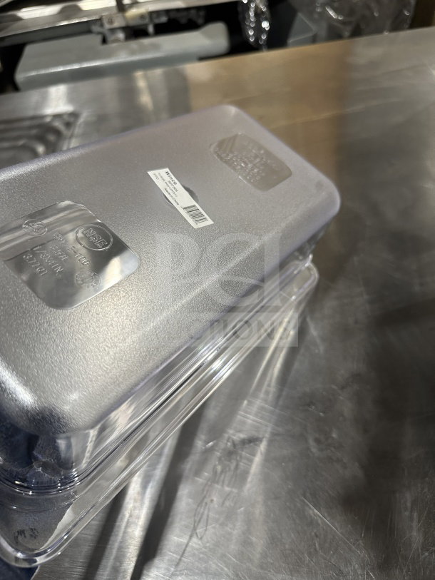 Winco SP7304 Commercial 1/6-Size Clear Polycarbonate Food Pan, new condition, visible NSF markings, on metal surface.