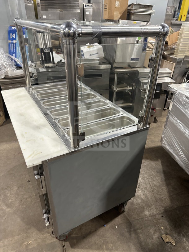 Leader stainless steel mobile refrigerated salad bar with glass cover and multiple compartments on casters, commercial use.