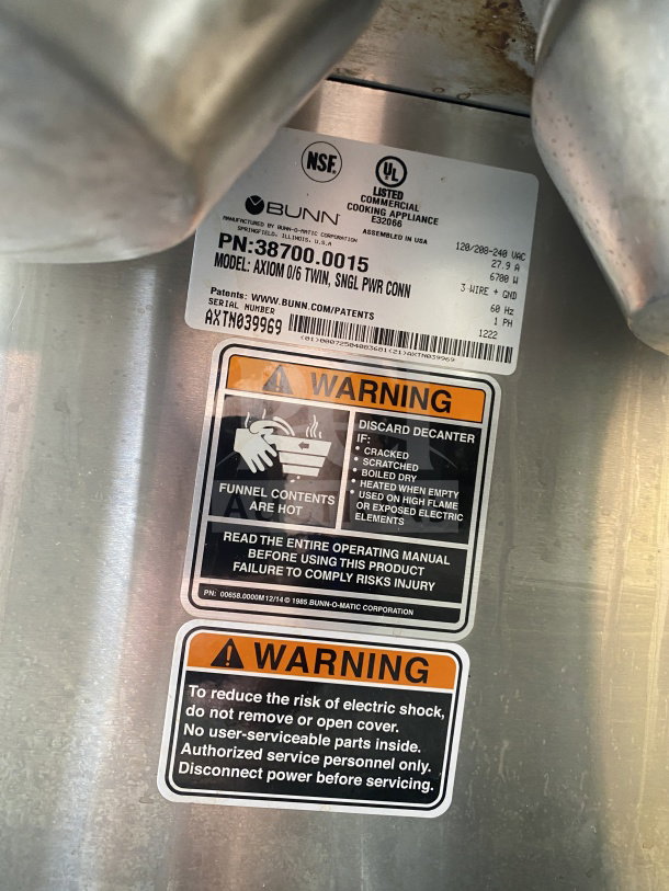 Bunn AXIOM 0/6 TWIN coffee brewer label showing model, warnings, and specifications. Stainless steel construction, commercial use.