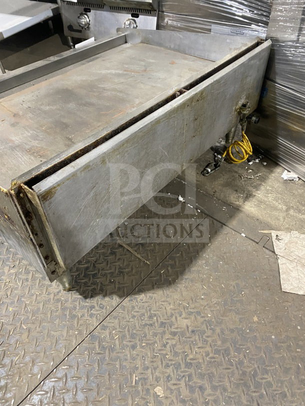 Star Max commercial stainless steel gas griddle with back and side splashes, on legs. Used condition with visible wear.