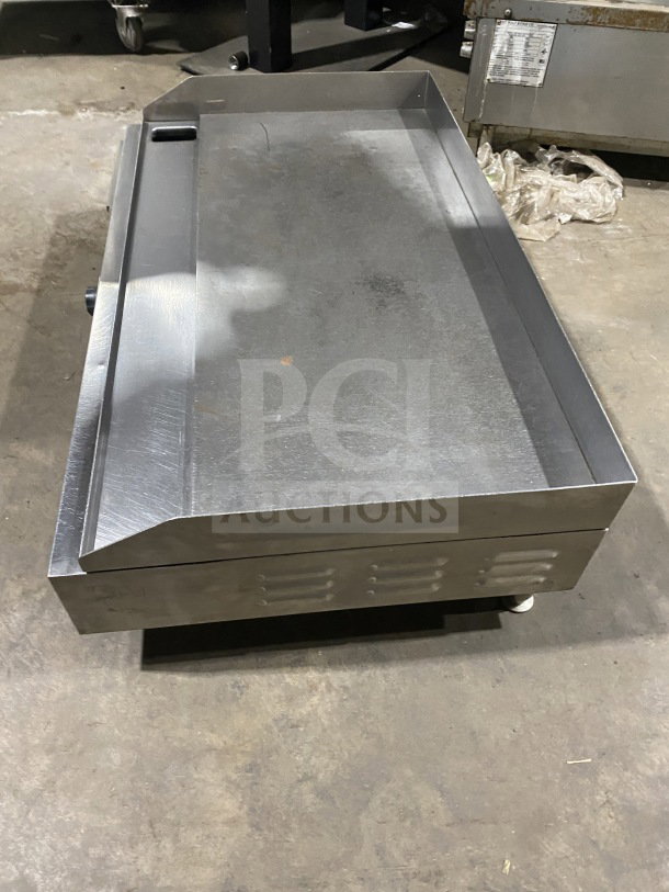 Commercial stainless steel electric countertop griddle with side and back splash, on legs, in good condition.