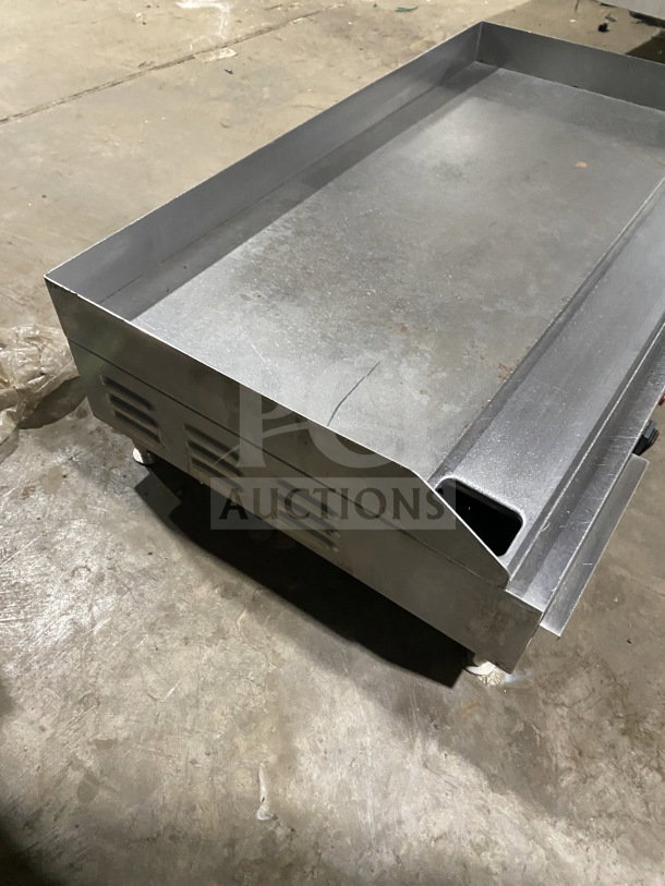 Commercial stainless steel electric countertop griddle with side and back splash, on legs, in fair condition.