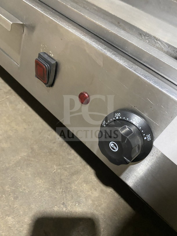 Commercial stainless steel electric griddle with adjustable heat dial, side and back splash, on legs; features durable build.