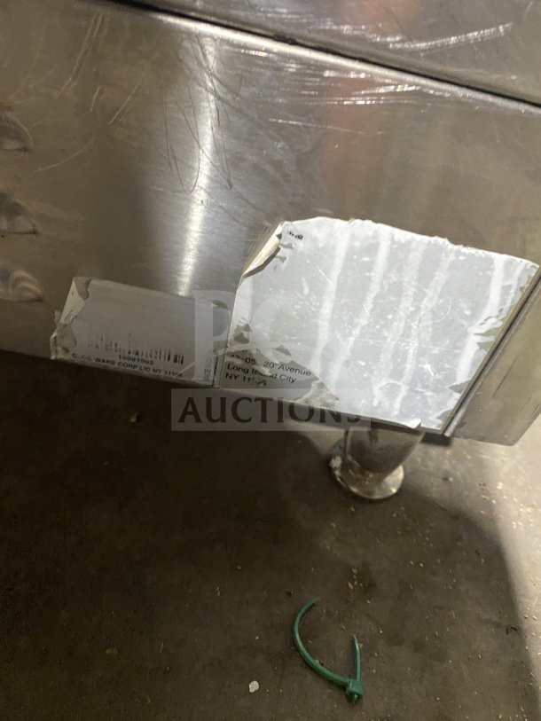 Commercial stainless steel electric countertop griddle with side and back splash. Visible leg supports. Scratched surface.