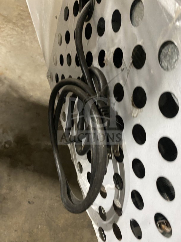 Coiled electrical cord of a Leader LB48SC commercial refrigerator, showing perforated vented back panel.