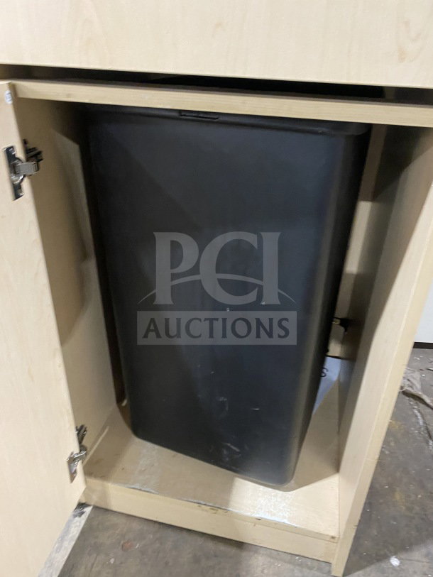 Commercial wooden waste enclosure with tray holder, featuring hinged cabinet door and black waste bin. Good condition.
