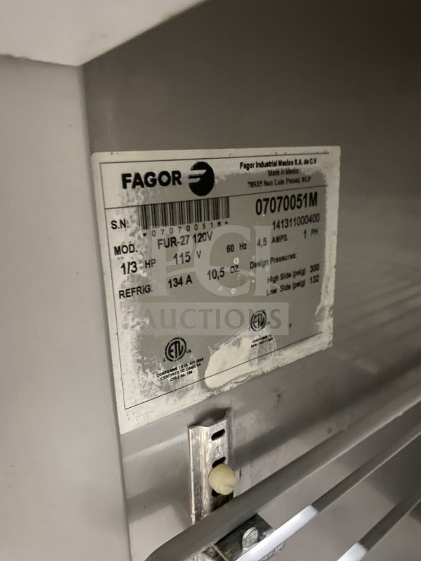 Fagor FUR-27 stainless steel undercounter refrigerator with poly coated wire rack; model tag SN: 07070051M, 115V, on casters.