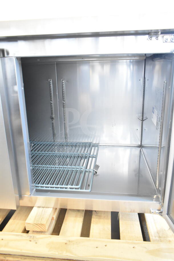 Avantco 178SSPPT3 commercial pizza prep table, new scratch and dent, 115V, shown on pallet, interior view with shelving.
