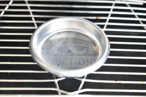Shiny metal component from the Nuova Simonelli Oscar II AD espresso machine on a metal grate.