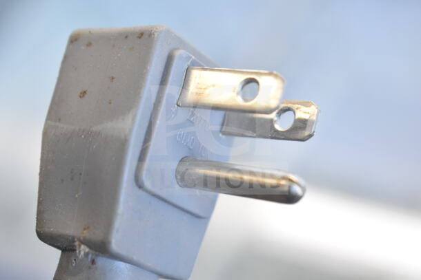 Close-up of a power plug for AHT RIO S 100 Commercial Freezer Merchandiser, 115 Volts, showing prongs and minor wear.