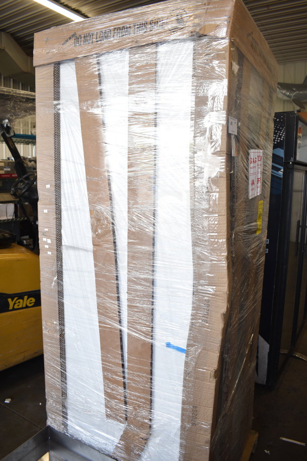 Large appliance in packaging, labeled "Do Not Load From This Side." Wrapped in plastic, indicating new condition with noted scratches and dents.