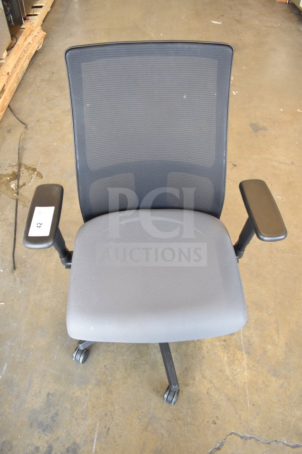 Mesh office chair on casters with adjustable arms, gray seat, and label indicating lot number 42. Available in quantity 12.