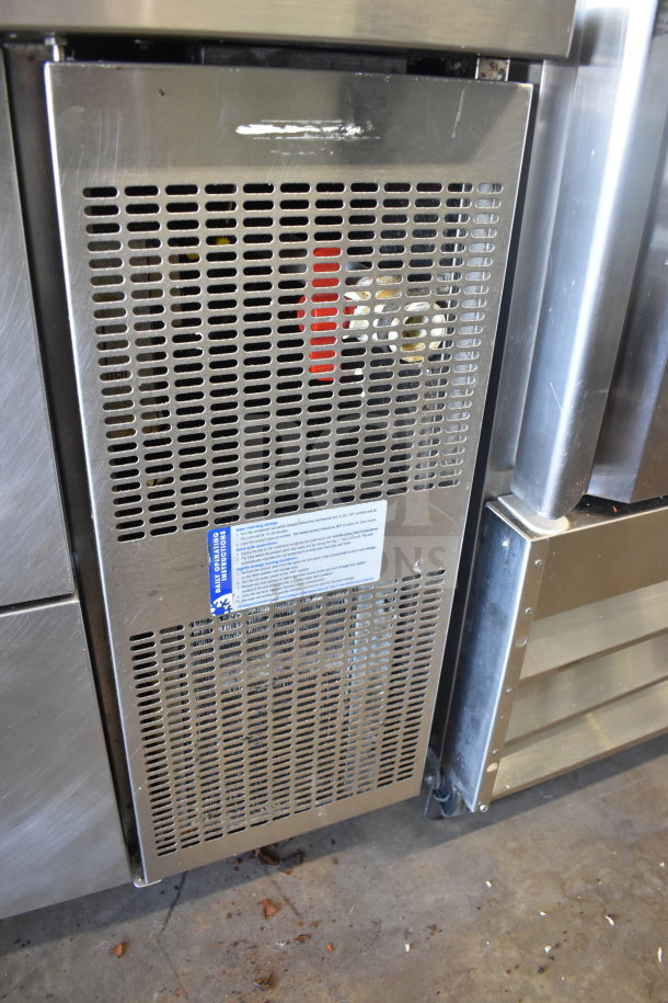 Commercial pizza prep table with four drawers, stainless steel finish, on casters. Ventilation panel and instructions label visible.