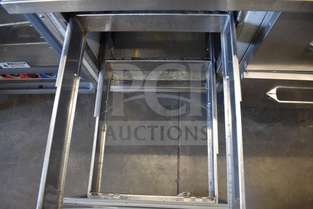 Commercial pizza prep table with four drawers on casters, 115 volts, 1 phase, stainless steel, visible wear.