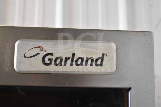 Garland SunFire commercial gas range, 6 burners, salamander cheese melter, oven, overshelf, logo visible, stainless steel.