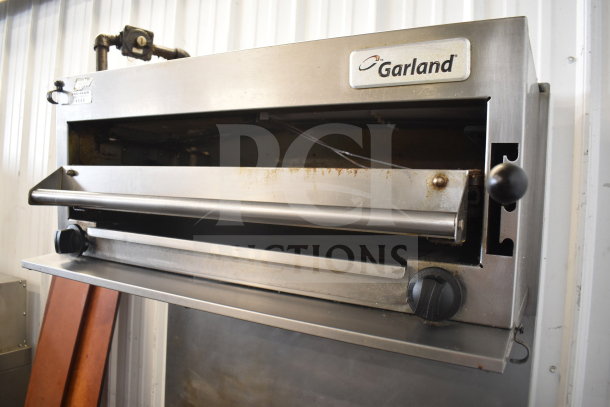 Garland SunFire commercial gas range with 6 burners, salamander cheese melter, oven, and over shelf. Visible Garland branding.