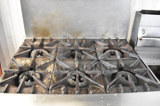 Garland SunFire commercial gas-powered 6-burner range with oven, salamander cheese melter, and overhead shelf. Used condition.