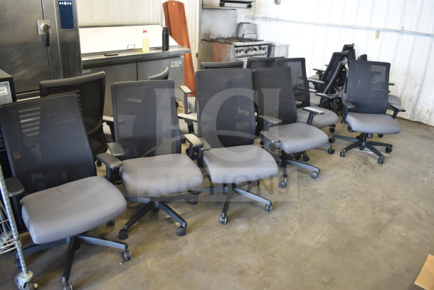 Sixteen office chairs on casters, black mesh back, gray seat, ergonomic design, adjustable arms, good condition.