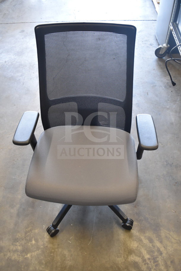 Black office chair with mesh back, padded seat, armrests, and casters. Auction includes 16 chairs total. Optimal for office use.