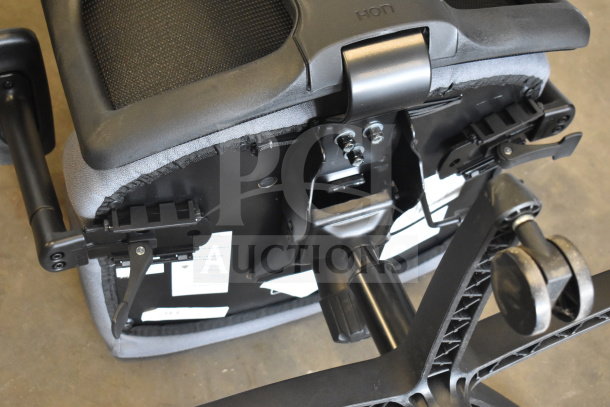 Black and gray HON office chair with casters, underside view showing adjustment mechanisms and brand label.