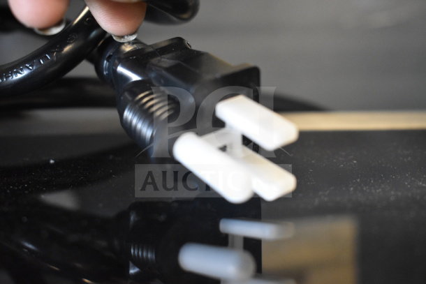 Close-up of a power plug connected to the Avantco 177W50 electric countertop food warmer, new with minor scratches.
