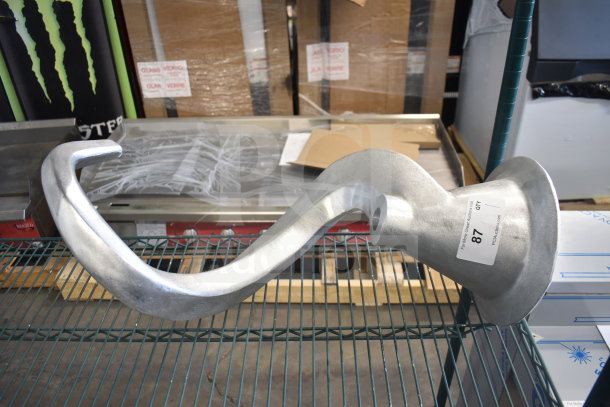 Brand new commercial dough hook attachment with minor scratches and dents, shown on a display shelf with auction label.
