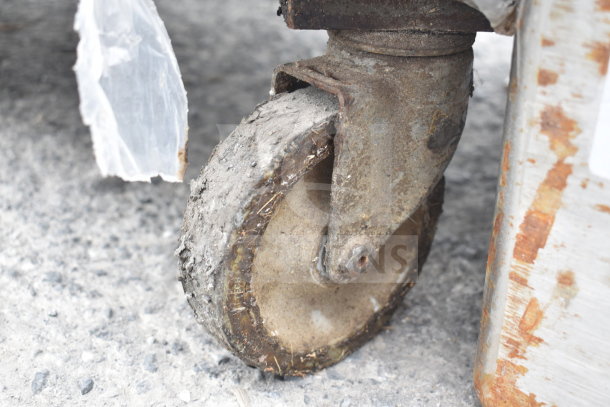Rusty metal caster wheel on concrete, suggesting wear. Likely from storage or transport equipment accompanying baking pans.
