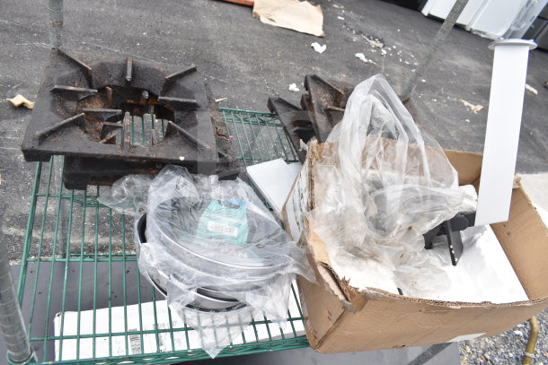 Green 3-tier wire shelving unit on casters with various contents. Includes a rusted metal part, wrapped cookware, and boxed items.