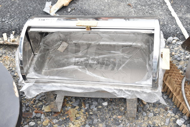 Stainless steel roll top chafer, new condition, with protective plastic wrap. Item tag visible on top, marked "128."