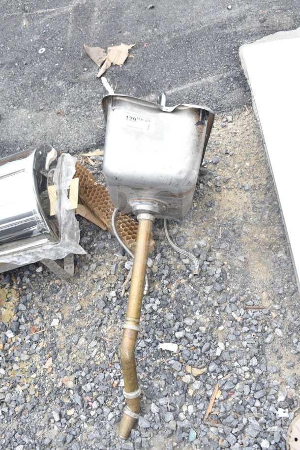 Single bay drop-in sink with faucet and handles, showing wear. Visible tag labeled "129" with attached pipes, on gravel surface.