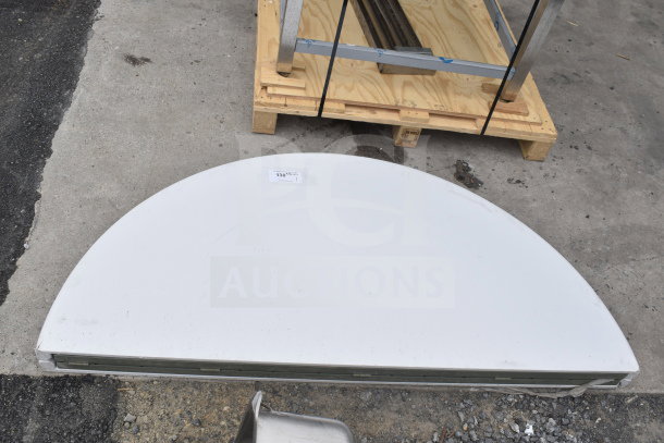 Brand new scratch and dent round bi-fold folding table, partially folded, shows minor surface imperfections, auction tag visible.