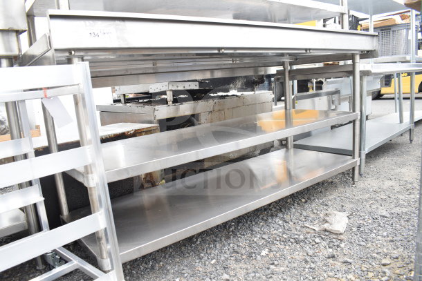 Brand new scratch and dent stainless steel table with two under shelves, suitable for storage, visible labels present.