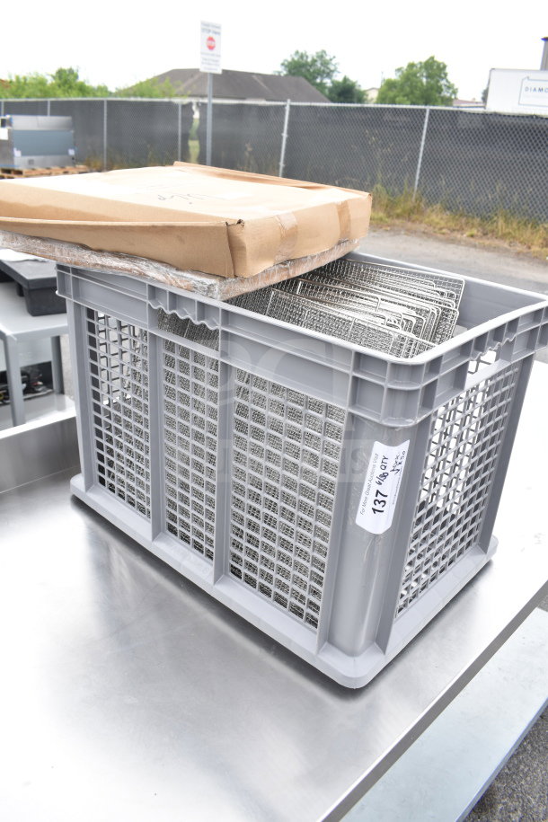 Brand new stainless steel mesh tray racks in a gray plastic bin; lot label suggests 50 units, scratch and dent condition.