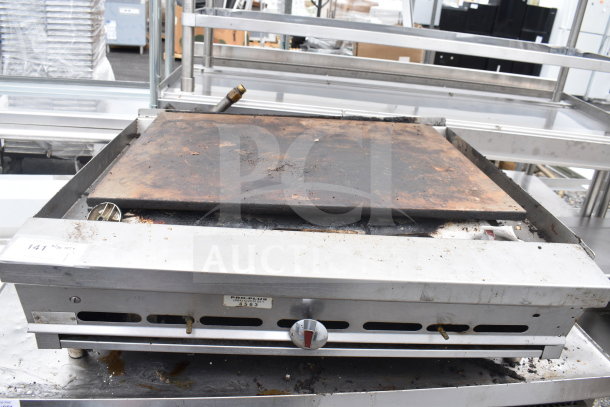 Commercial countertop gas-powered flat top griddle with metal casing. Shows signs of use; includes temperature control knob and vent slots. Serial tag visible.