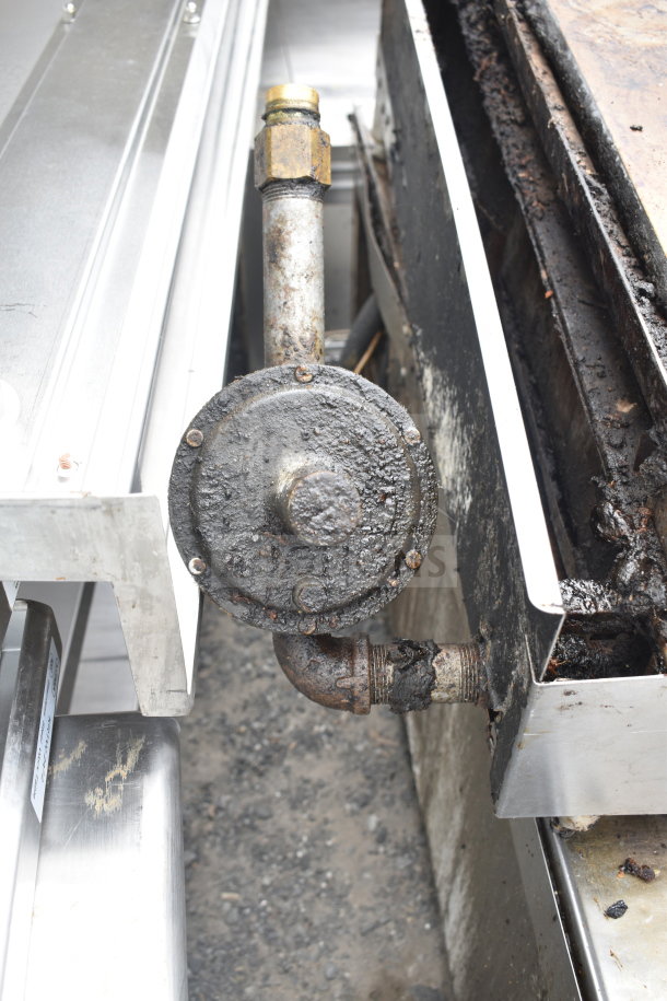 Commercial countertop gas-powered flat top griddle, used condition, visible grease buildup, gas connection details shown.