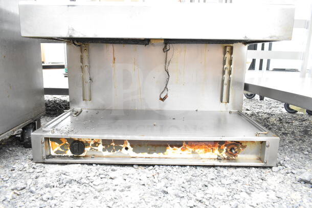 Commercial cheese melter in used condition, showing surface rust and discoloration. Features stainless steel exterior.