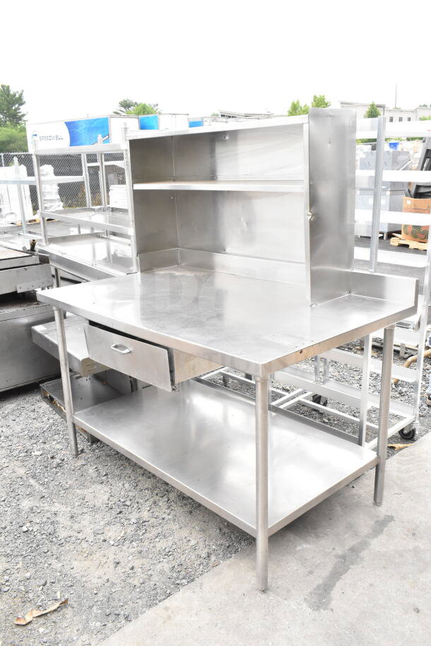 Stainless steel table with overhead shelf, drawer, and undershelf. Ideal for storage and workspace. Good condition.