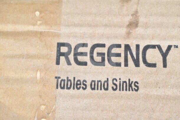 Cardboard box labeled "Regency Tables and Sinks," part of a scratch and dent auction lot including work tables and a Cantonese wok.