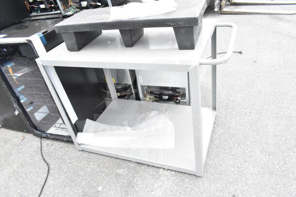 Brand new gray 2-tier cart and black dunnage rack, scratch and dent items. Protective wrapping partially visible.