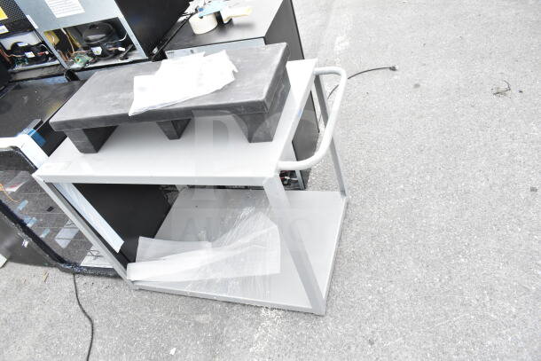 Gray two-tier cart and black dunnage rack, brand new scratch and dent, visible in industrial setting.