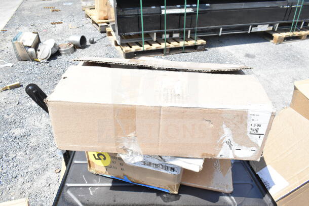 Cardboard boxes labeled "Scratch and Dent" containing 18 new items, including a Speed Rail, Canopy Tent, and Serving Trays.