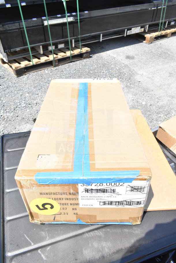 Cardboard box labeled with industrial markings, tape, and a yellow sticker, containing one of 18 new scratch and dent items for auction.