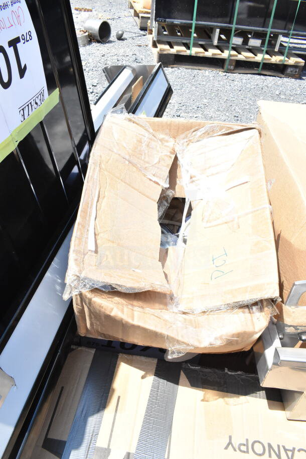 Open cardboard box revealing scratch and dent items, includes speed rail, canopy tent, serving trays. Box has visible tears.